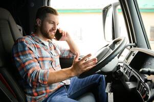 giovane professionale autista comunicare al di sopra di mobile Telefono mentre guida un' camion. foto