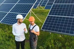 uomo d'affari e lavoratore vicino solare energia batterie. attività commerciale cliente mostrando fotovoltaico dettaglio per caposquadra. Due uomini fabbricazione affare. foto