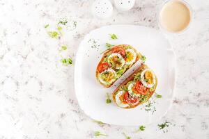 delizioso crostini con avocado, bollito uovo, pomodori e microgreen su un' bianca piatto. salutare mangiare, prima colazione. cheto dieta cibo. di moda cibo. superiore Visualizza foto