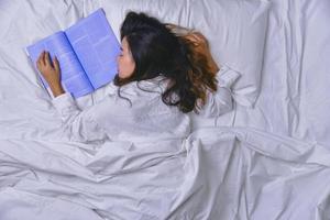 giovane donna che dorme nel letto. vista dall'alto della giovane donna sdraiata che dorme bene a letto. la ragazza che ha letto il libro a letto e dorme. dormire relax, relax, sonno, educazione, sonno profondo. foto