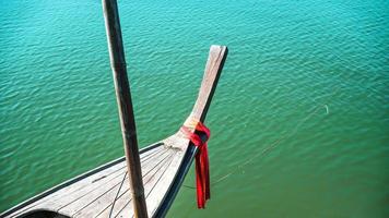 foto della testa della nave di prua con un panno rosso legato. vista dalla testa della tradizionale barca in legno con panno rosso legato. barca da pesca, barca longtail tradizionale thailandese, mare delle andamane.