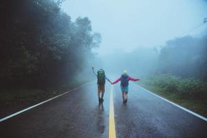 amante uomo asiatico e donne asiatiche viaggiano nella natura. camminare sul percorso stradale. viaggiare felicemente nella natura. in mezzo alla nebbia piovosa. foto