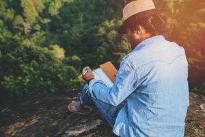il viaggio dell'uomo asiatico si rilassa durante le vacanze. sedili relax leggere libri su scogliere rocciose. sulla montagna. in Thailandia