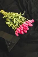 un' mazzo di rosa fiori su nero elegante biancheria con un Aperto il computer portatile. foto