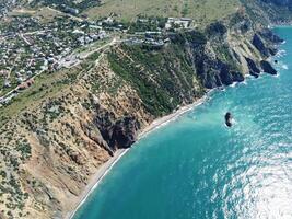 aereo Visualizza a partire dal sopra su calma azzurro mare e vulcanico roccioso sponde. piccolo onde su acqua superficie nel movimento sfocatura. natura estate oceano mare spiaggia sfondo. nessuno. vacanza, vacanza e viaggio concetto foto