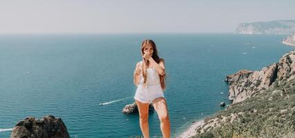 donna estate viaggio mare. contento turista godere assunzione immagine all'aperto per ricordi. donna viaggiatore in posa al di sopra di mare baia circondato di vulcanico montagne, condivisione viaggio avventura viaggio foto