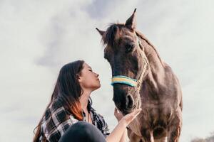 giovane contento donna con sua pony cavallo nel sera tramonto luce. all'aperto fotografia con moda modello ragazza. stile di vita umore. concetto di all'aperto cavalcare, gli sport e ricreazione. foto