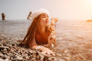 donna viaggio mare. contento turista godere assunzione immagine su il spiaggia per ricordi. donna viaggiatore nel Santa cappello sembra a telecamera su il mare baia, condivisione viaggio avventura viaggio foto