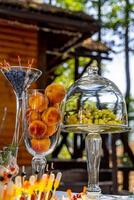 piatti con mirtilli e Pesche. frutta su festa tavolo. uva sotto bicchiere trasparente cupola coperchio. dolce su il festivo tavolo. foto