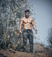 uomo nel militare pantaloni in piedi su natura sfondo. Perfetto maschio corpo. foto