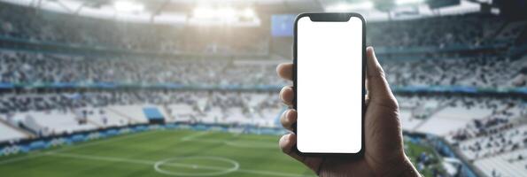 ai generato mano Tenere smartphone con vuoto bianca schermo contro calcio o calcio stadio sfondo per modello presentazione foto