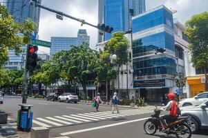 persone chi siamo attraversamento un' zebra attraversamento attrezzata con traffico luci su un urbano strada, Indonesia, 2 marzo 2024. foto