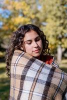 ritratto di giovane donna felice in caldo plaid nella foresta autunnale foto