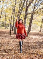 giovane donna felice che cammina nella foresta autunnale foto