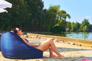 riposo, relax, estate spiaggia. un' donna prende un' prendere il sole su un ottomano cuscino foto