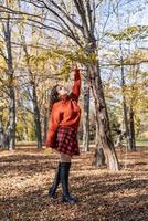 giovane donna felice che cammina nella foresta autunnale foto