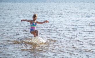 giovane contento bambino ragazza di europeo aspetto età di 6 avendo divertimento nel acqua su il spiaggia e spruzzi,tropicale estate vocazioni,vacanze.a bambino gode il mare.famiglia vacanze concetto.copia spazio. foto