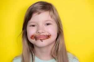 contento e ridendo poco ragazza mangiare cioccolato sporco viso. vicino su di ragazzo con sporco viso nel cioccolato . foto