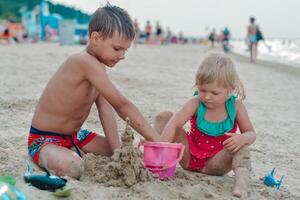 fratello e sorella fabbricazione sabbia castello su il spiaggia nel caldo estate giorno.famiglia estate vacanze concetto.chiudi su. alto qualità foto
