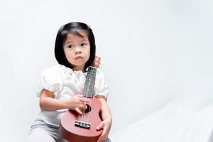 bambina sta suonando l'ukulele. su sfondo bianco. foto