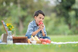 contento famiglia godendo un' picnic nel il parco, con bambini avendo divertimento seduta, circondato di natura foto