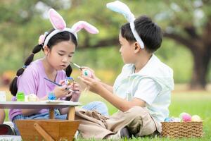 contento famiglia godendo un' picnic nel il parco, bambini seduta e colorazione loro bellissimo Pasqua uova. foto