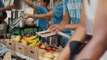 a cibo viaggio, povero femmina sedia a rotelle utente riceve gratuito cibo e disposizioni. multietnico volontari nel blu maglietta distribuzione fresco frutta e caldo pasti per Di meno privilegiato. avvicinamento, treppiedi. foto