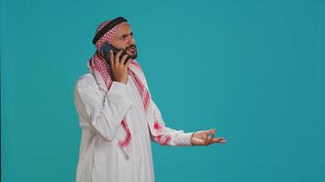 musulmano modello risposte mobile Telefono chiamata su senza fili dispositivo, comunicare su a distanza telefono linea. giovane persona che rappresentano islamico tradizione con costume e foulard, segreteria Chiacchierare. foto