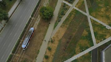 superiore Visualizza di moderno tram nel città con parco. clip. tram nel movimento su rotaie nel città nel estate. tram cavalcate a parco vicolo nel città foto