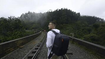 uomo su escursioni a piedi viaggio su tropicale ponte. azione. uomo su escursioni a piedi pista con pietra ponte e ferrovia. uomo passeggiate su pietra ponte nel tropicale montagne foto