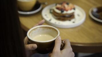 avvicinamento di bellissimo donna avendo pranzo nel bar con caffè e dolce. azione filmato. donna bevande caffè con bellissimo dolce nel bar. bellissimo estetico pranzo con dolce e caffè nel bar foto