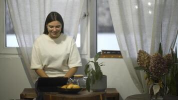 giovane donna bevande tè e sembra a tavoletta nel bar. media. alunno orologi video su rompere e bevande tè nel accogliente bar. giovane donna è rilassante Guardando tavoletta e avendo tè nel bar foto