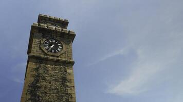 storico orologio Torre con pittoresco nuvole e blu cielo su il sfondo. azione. Basso angolo Visualizza di il antico mattone Torre. foto