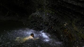 bambino ragazzo nuoto nel montagna stagno con cascata. creativo. bambino su estate vacanza rinfrescante nel fiume. foto