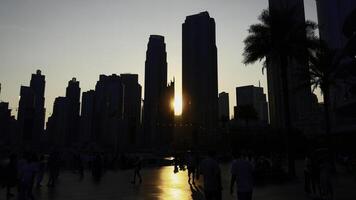 tramonto fra grattacielo torri e a piedi irriconoscibile folla di le persone. azione. centrale quartiere di dubai città. foto