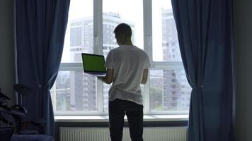 indietro Visualizza di un' giovane uomo nel bianca t camicia Lavorando su il computer portatile con verde croma chiave schermo. media. concetto di utilizzando moderno tecnologie per a distanza opera. foto