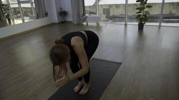 giovane donna è fare yoga nel un' bianca camera pieno con luce. media. il ragazza esegue yoga sta e elementi vicino il grande finestra. foto