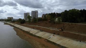 costruzione e rafforzamento di un' nuovo sicurezza argine lungo il fiume. clip. aereo Visualizza ov il miglioramento città la zona. foto