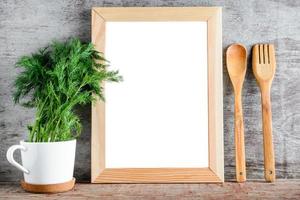 una cornice di legno vuota e accessori da cucina su un muro grigio. foto