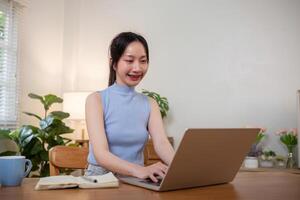 giovane donna studiando mentre seduta a il tavolo con il computer portatile computer e taccuino a casa foto