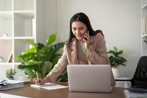 opera a partire dal casa. donna d'affari utilizzando il computer portatile computer e smartphone nel sua camera. eco amichevole donna d'affari Lavorando su scrivania, libero professionista foto