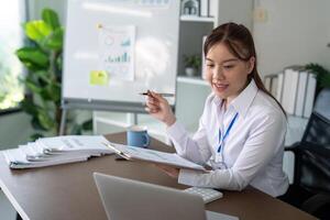 asiatico attività commerciale donna utilizzando il computer portatile per analisi grafico finanziario bilancio rapporto e pianificazione per futuro nel ufficio scrivania foto