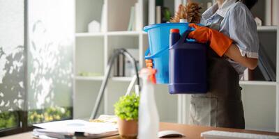 giovane donna pulizia per disinfettare il ufficio ufficio pulizia personale pulizia domestica. femmina addetto alle pulizie Tenere un' secchio con pulizia forniture foto