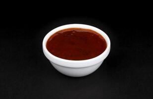 griglia salsa nel ciotola isolato su nero sfondo foto
