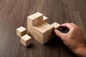 attività commerciale strategia concettuale idea. umano mano costruisce pila di di legno blocchi. foto