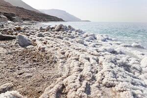 naturale paesaggio di morto mare costa con il sedimento di sale su il terra, Giordania. foto