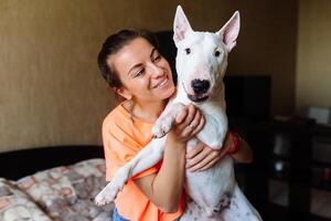 carino ragazza petting sua Toro terrier .Bellissima ragazza avendo divertimento con sua Toro terrier e godendo se stessa. ragazza e sua Toro terrier avendo divertimento interno. foto