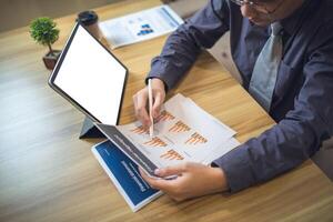 uomo d'affari analizzando statistica su documenti con un' modello schermo il computer portatile a un' spazio di lavoro foto