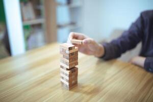 attività commerciale strategia concetto con mani giocando un' di legno bloccare Torre gioco, simboleggiante rischio e stabilità. pianificazione rischio gestione foto