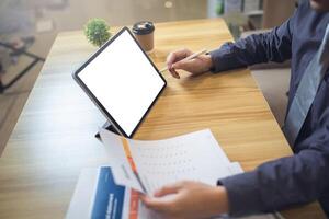 uomo d'affari analizzando statistica su documenti con un' modello schermo il computer portatile a un' spazio di lavoro foto